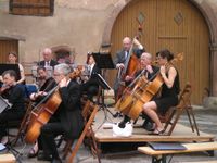 Das Bild zeigt das Orchester bei einem Konzert im Innenhof des Château de Lorentzen.